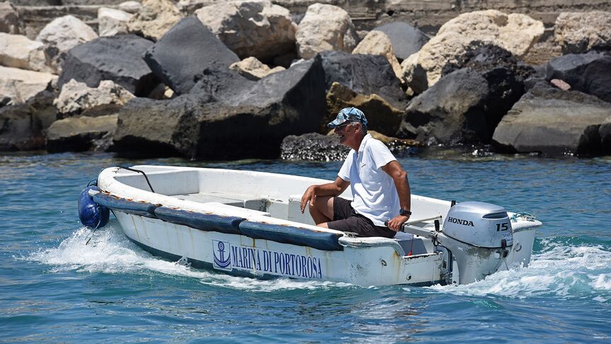 Homme sur un bateau, équipé d’un moteur BF15 en zone côtière. 