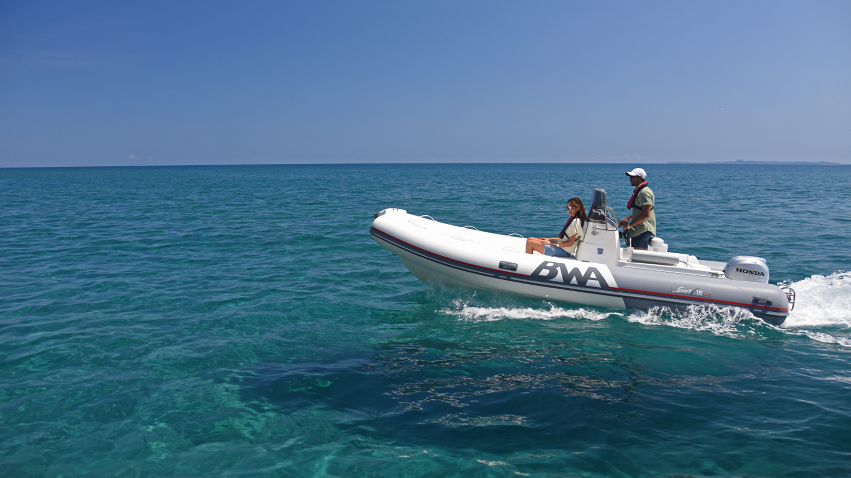 Couple sur un bateau de profil équipé d'un moteur Honda BF, en mer.